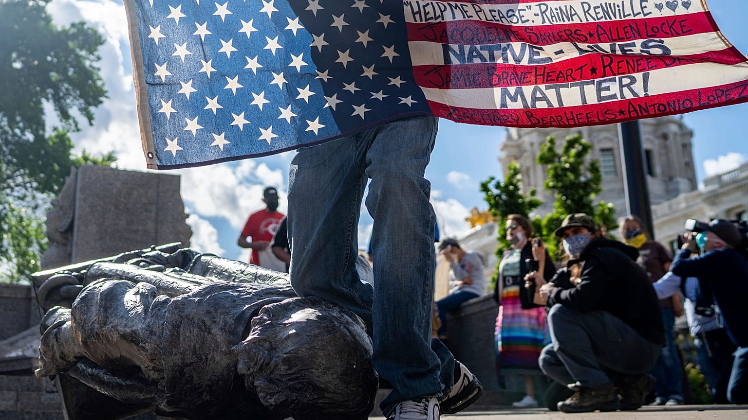 Un Amérindien Lakota presse symboliquement son genou sur la statue de Christophe Colomb à Saint Paul - capitale du Minnesota - le 10 juin 2020