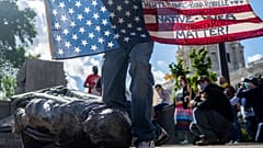 Un Amérindien Lakota presse symboliquement son genou sur la statue de Christophe Colomb à Saint Paul - capitale du Minnesota - le 10 juin 2020