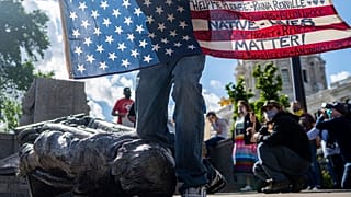 Un Amérindien Lakota presse symboliquement son genou sur la statue de Christophe Colomb à Saint Paul - capitale du Minnesota - le 10 juin 2020