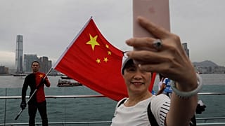 Pro-China supporters take a selfie with a Chinese national flag to support police and anti-violence during a rally at a park in Hong Kong.
