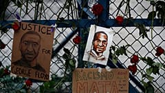 Images of George Floyd hang surrounded by roses on a security barrier outside the US embassy in Mexico City