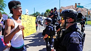 A protester and police face each other during a demonstration near a private event attended by President Donald Trump, Thursday, June 11, 2020.