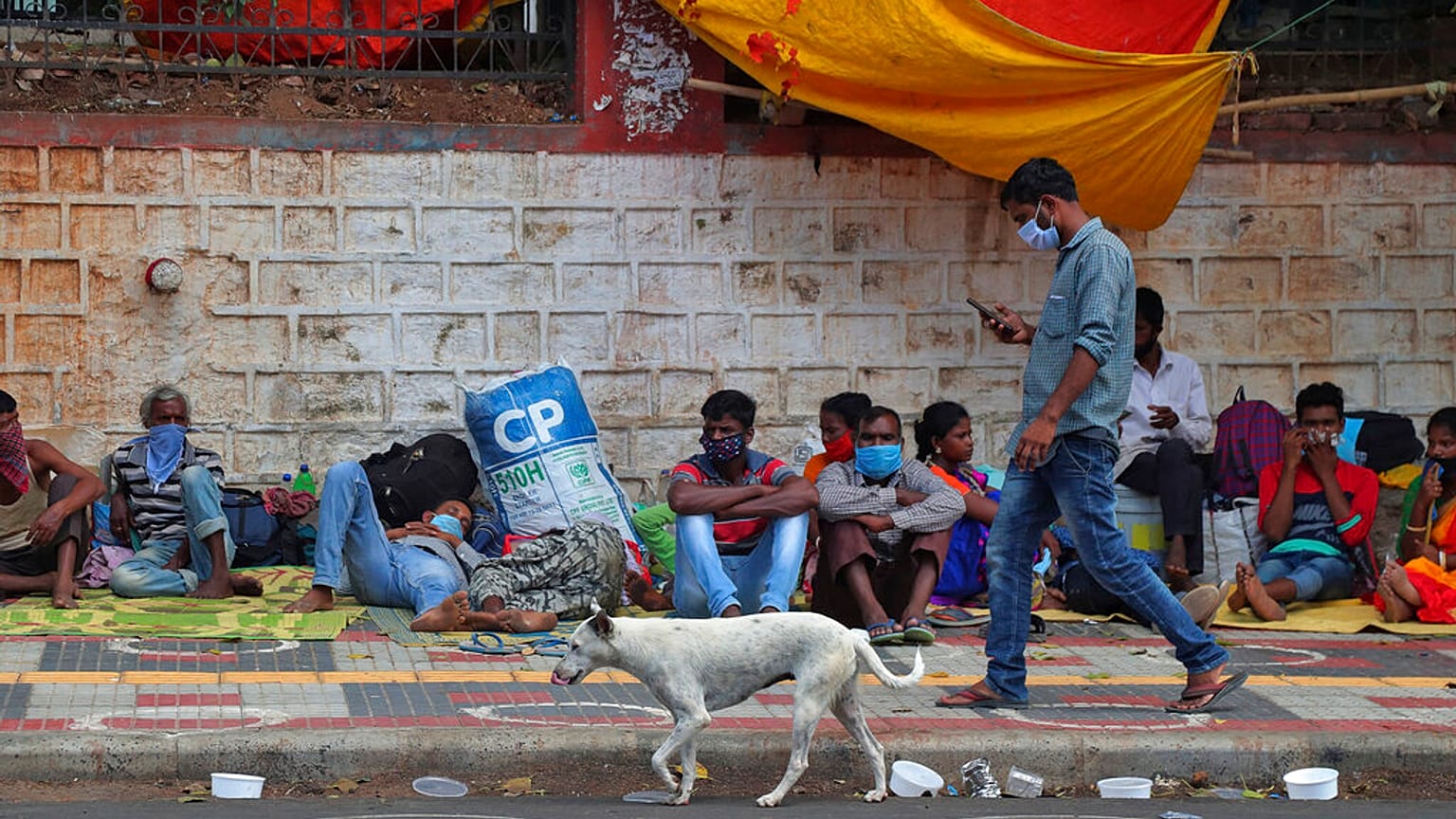 Migrant workers from other states rest on a pavement as they wait for trains to their home states in Hyderabad, India