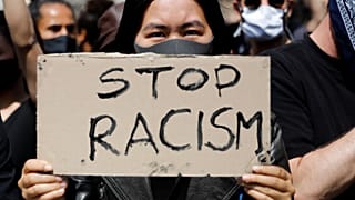 Una donna mostra un cartello "Stop al razzismo", durante a una manifestazione a Berlino (06/06/2020)