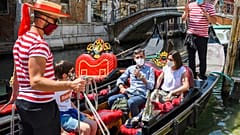 Gondoliers go with customers for a gondola ride on a canal in Venice on June 12, 2020