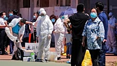 Workers put on protective suits as they wait for people living near the Xinfadi wholesale market arrive to get a nucleic acid test at a stadium in Beijing, June 14, 2020