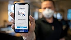 A man holds a mobile phone showing Norway's National Institute of Public Health new mobile app infection stop for infection tracking, in Oslo, Norway, Friday April 17, 2020