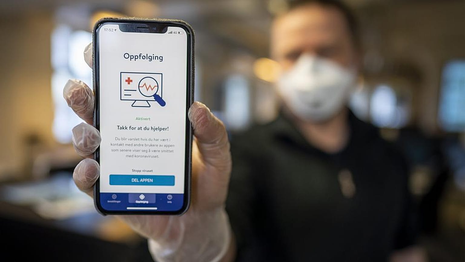 A man holds a mobile phone showing Norway's National Institute of Public Health new mobile app infection stop for infection tracking, in Oslo, Norway