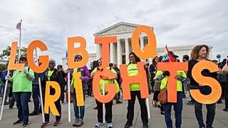 FILE - In this Oct. 8, 2019, file photo, supporters of LGBTQ rights hold placards in front of the U.S. Supreme Court in Washington.
