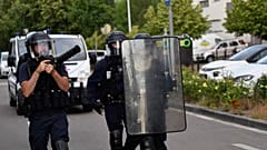 Police walk carrying a shield and a tear gas canister launcher in the Gresilles area of ​​Dijon, eastern France, on June 15, 2020.