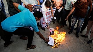 An Indian man burns a photograph of Chinese president Xi Jinping during a protest against China in Ahmedabad, India, Tuesday, June 16, 2020.