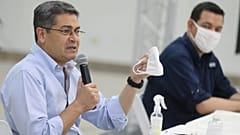 Honduras President Juan Orlando Hernandez holds a face mask during a press conference