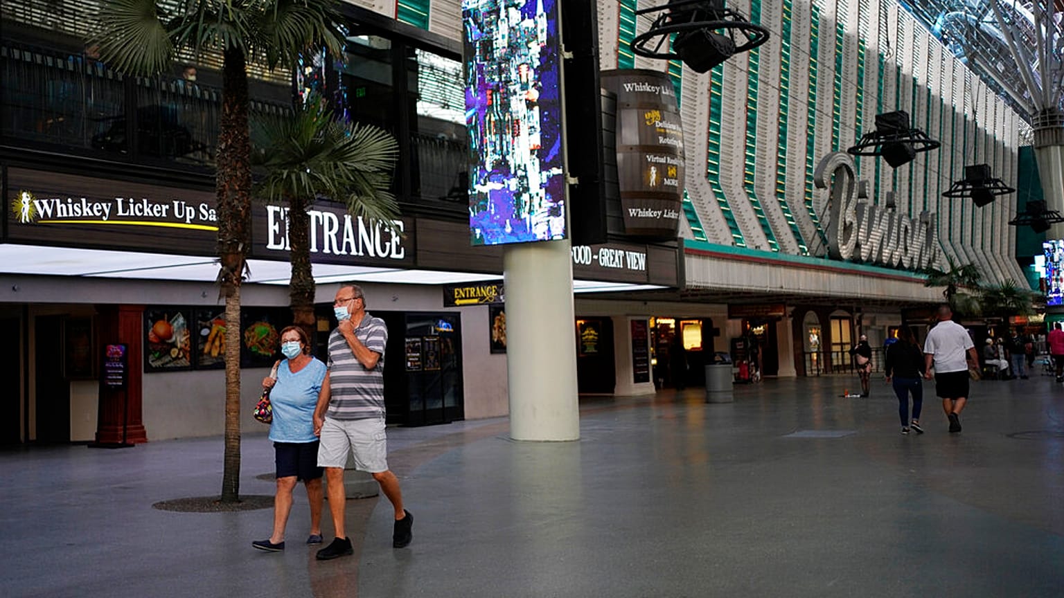 People in masks walk by Binion's casino Monday, June 15, 2020, in Las Vegas