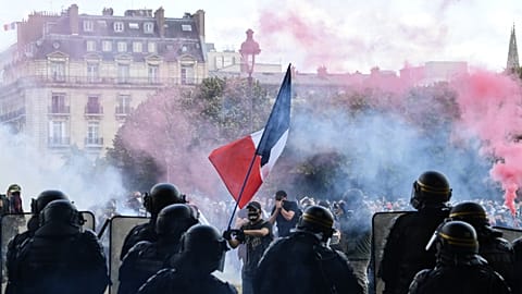 Protesters with a French flag face police during clashes on the Invalides esplanade at a demonstration in Paris. 16 June 2020