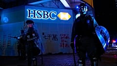Police stand guard in front of a vandalized HSBC bank