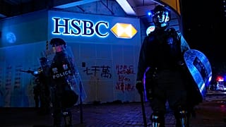 Police stand guard in front of a vandalized HSBC bank