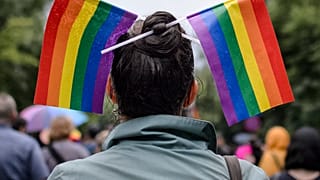 A woman with rainbow colored flags in her hair waits for the start of a gay pride parade in Bucharest, Romania, Saturday, May 20, 2017.