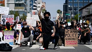 Des manifestants s'agenouillent dans un moment de silence devant le commissariat de Long Beach, le 31 mai 2020, lors d'une manifestation en mémoire à George Floyd.