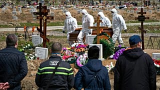Gravediggers in protective suits carry the coffin of a COVID-19 victim