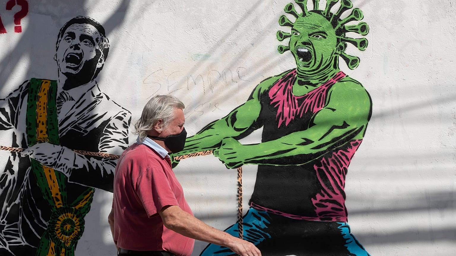 A man, wearing a protective face mask as a measure to curb the spread of the new coronavirus, walks past a mural in Sao Paulo, Brazi, June 19, 2020