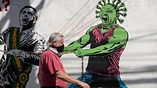 A man, wearing a protective face mask as a measure to curb the spread of the new coronavirus, walks past a mural in Sao Paulo, Brazi, June 19, 2020