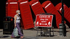 A sign requesting people stay two metres apart to try to reduce the spread of COVID-19 is displayed in front of "Out of Order" a 1989 red phone box sculpture