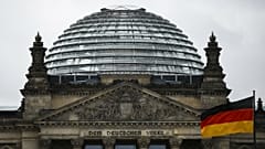 A German national flag waves in front of the German parliament building Reichtstag in Berlin, Germany