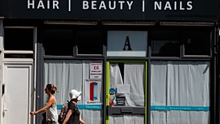 People walk past a closed hair and beauty salon in London, Tuesday, June 23, 2020. 