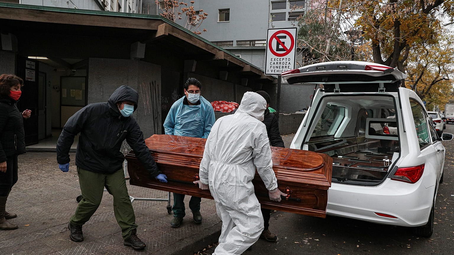 Empleados cargan el ataúd de un fallecido por Covid-19