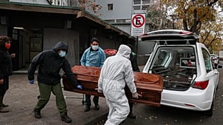 Empleados cargan el ataúd de un fallecido por Covid-19