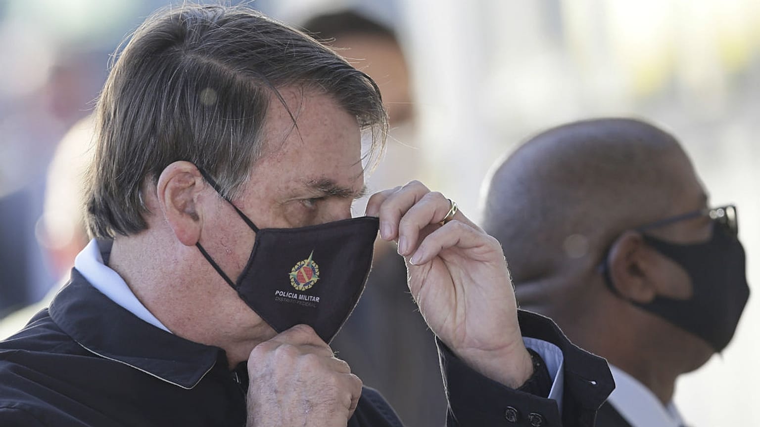 Brazil's President Jair Bolsonaro adjusts his face mask as he speaks to supporters while departing his official residence, Alvorada palace, in Brasilia, Brazil, Thursday, May 