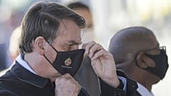 Brazil's President Jair Bolsonaro adjusts his face mask as he speaks to supporters while departing his official residence, Alvorada palace, in Brasilia, Brazil, Thursday, May 
