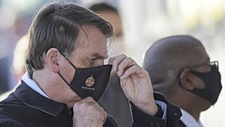 Brazil's President Jair Bolsonaro adjusts his face mask as he speaks to supporters while departing his official residence, Alvorada palace, in Brasilia, Brazil, Thursday, May 