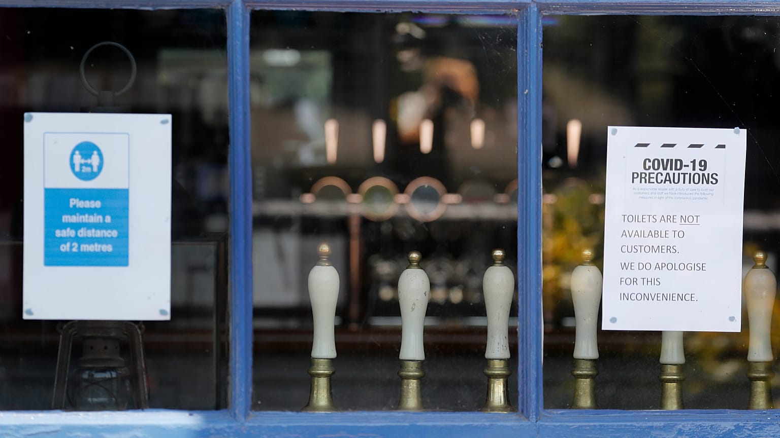 Draft tabs are seen through a window of a closed pub in London, Tuesday, June 23, 2020. Pubs are to reopen in a major easing of lockdown restrictions in England from July 4.