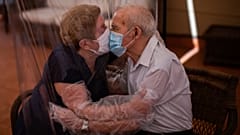 Agustina Cañamero, 81, and Pascual Pérez, 84, hug and kiss through a plastic film screen to avoid contracting the new coronavirus at a nursing home in Barcelona, Spain 