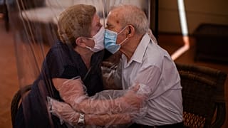 Agustina Cañamero, 81, and Pascual Pérez, 84, hug and kiss through a plastic film screen to avoid contracting the new coronavirus at a nursing home in Barcelona, Spain 