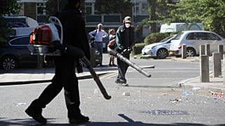 Volunteers clean up the streets following overnight violent confrontations in Brixton, London.
