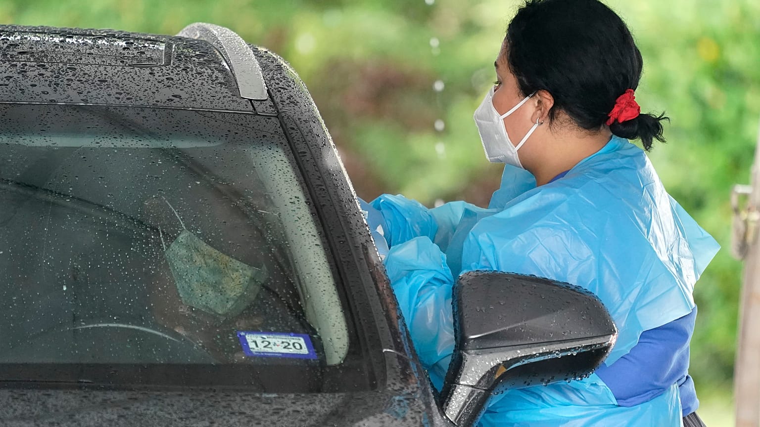 A healthcare professional, right, takes a sample from a patient at a United Memorial Medical Center COVID-19 testing site Wednesday, June 24, 2020