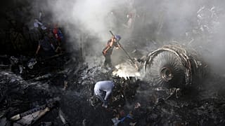 In this May 22, 2020 file photo, volunteers look for survivors of a Pakistan International Airlines plane that crashed in a residential area of Karachi, Pakistan.