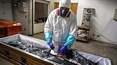 In this Saturday, June 27, 2020 file photo an employee takes the fingerprints of a woman who died from coronavirus, in Santiago, Chile.