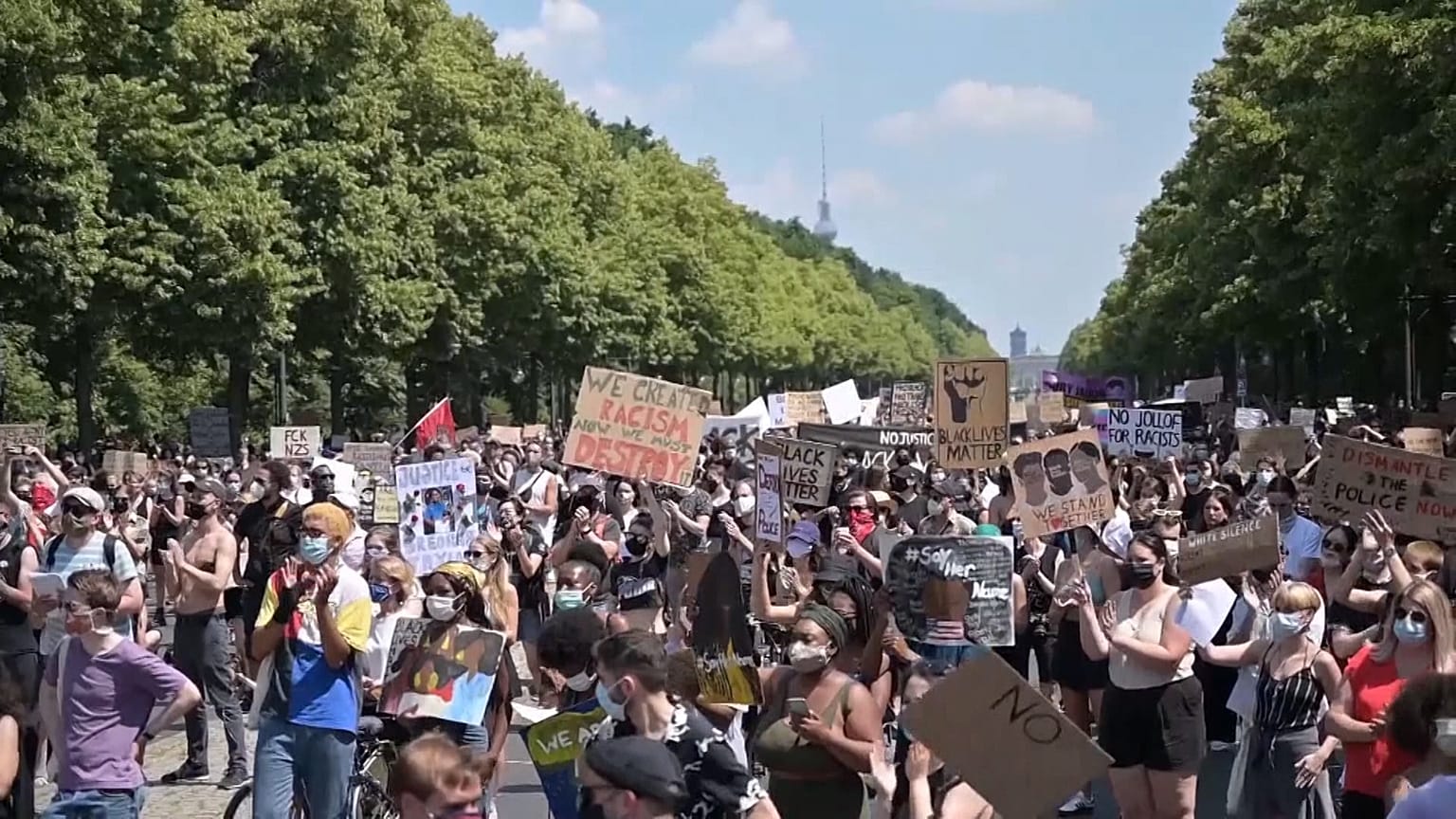 Protesters listening to speakers, holding placards