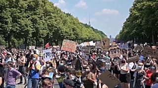 Protesters listening to speakers, holding placards