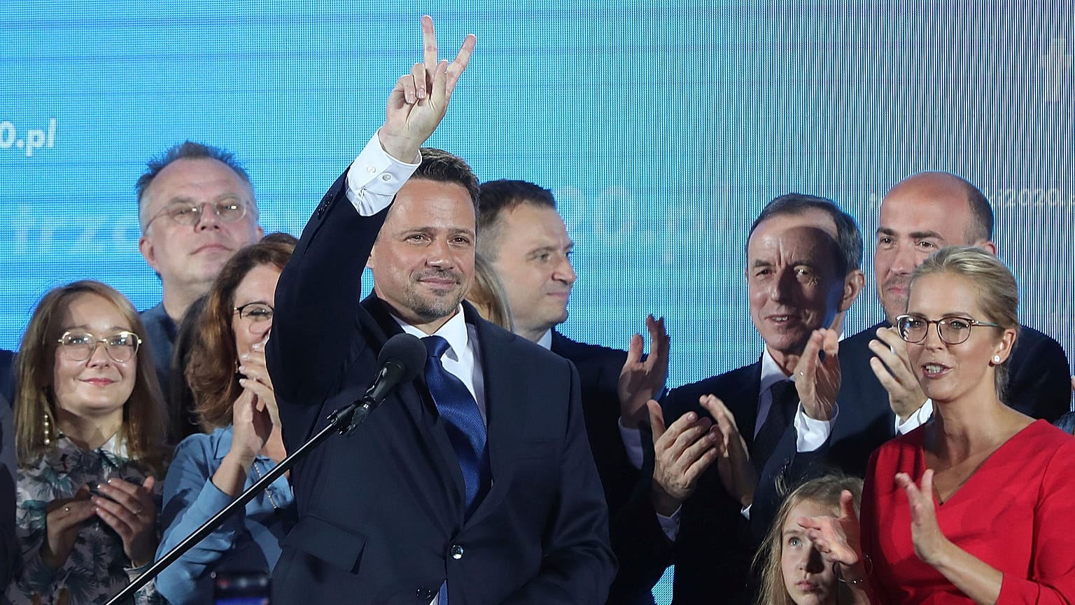 Warsaw Mayor Rafal Trzaskowski, front, reacts to exit poll after voting closed