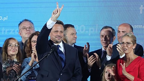 Warsaw Mayor Rafal Trzaskowski, front, reacts to exit poll after voting closed