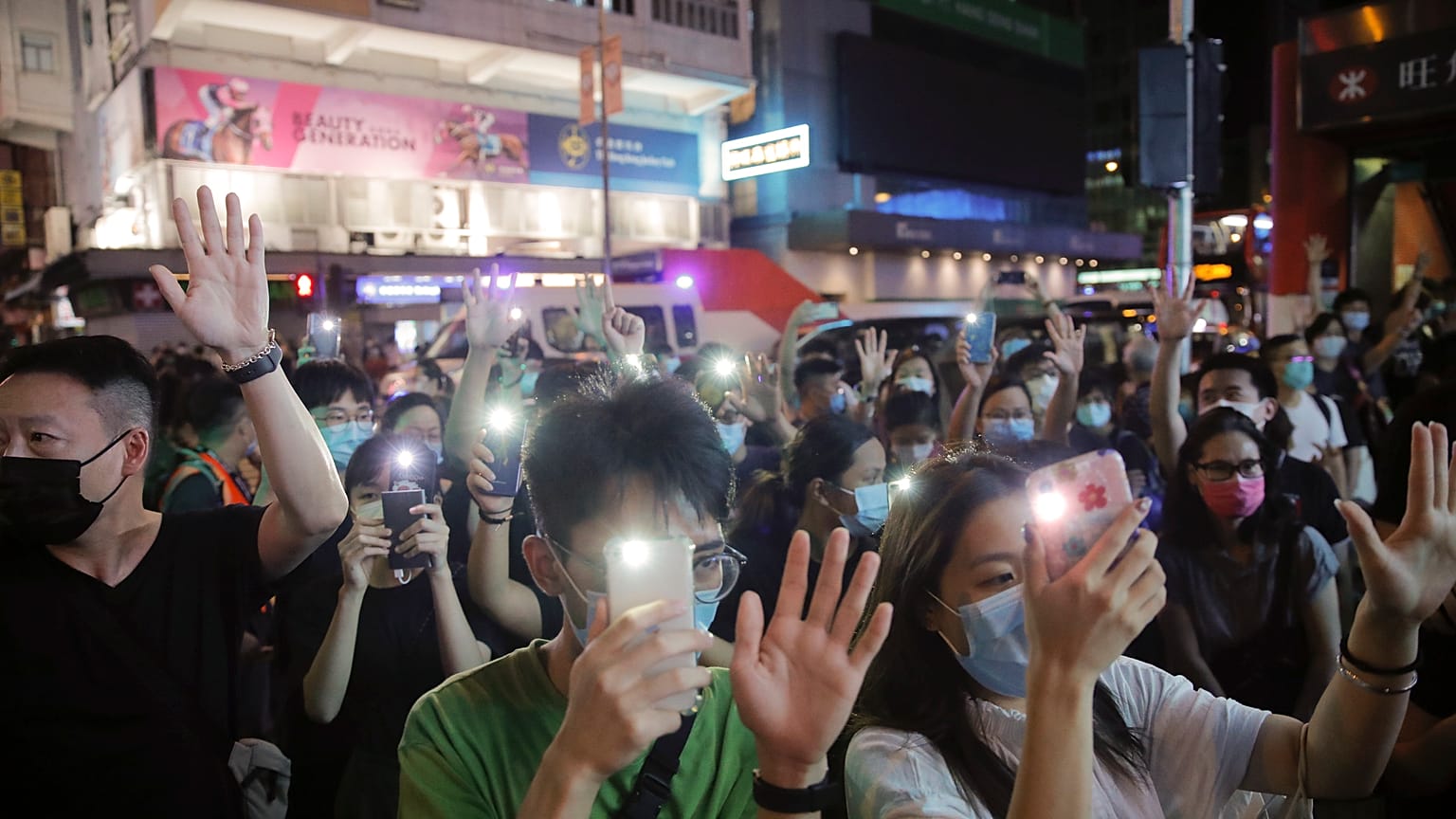 Protesters gesture with five fingers, signifying the "Five demands - not one less" during a protest in Mong Kok, Hong Kong, Friday, June 12, 2020. 