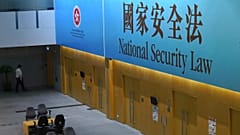 A government staff walks past a big banner featuring the Hong Kong National Security Law at the government headquarters in Hong Kong, Tuesday, June 30, 2020. 