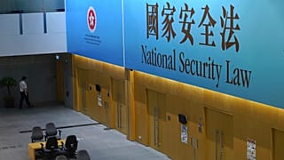 A government staff walks past a big banner featuring the Hong Kong National Security Law at the government headquarters in Hong Kong, Tuesday, June 30, 2020. 