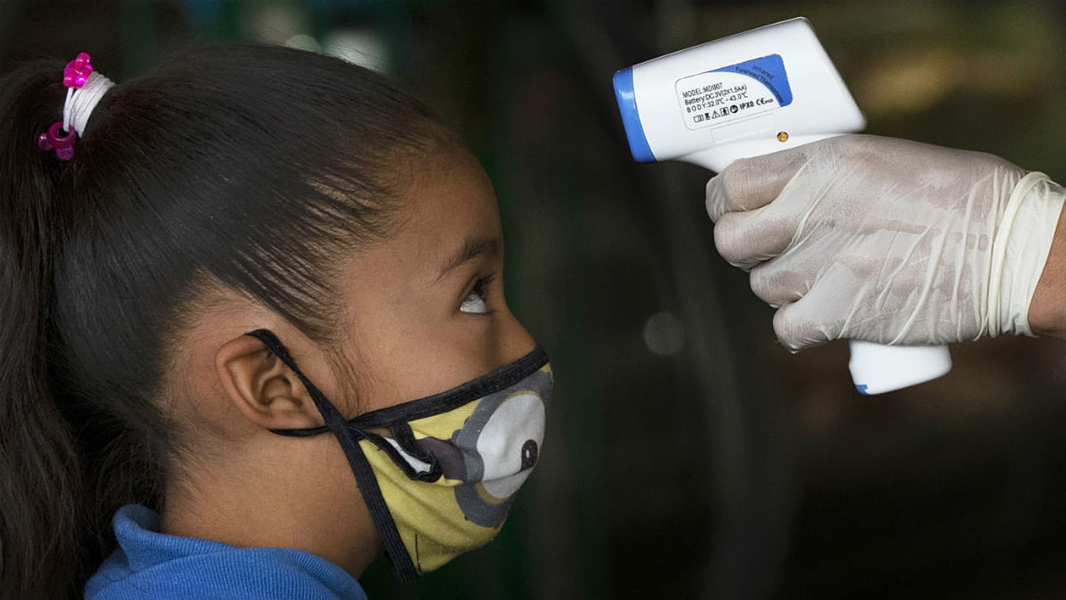A health worker takes a child's temperature to help curb the spread of the new coronavirus, at the Central de Abasto market in Mexico City