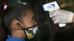 A health worker takes a child's temperature to help curb the spread of the new coronavirus, at the Central de Abasto market in Mexico City