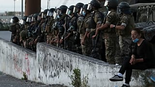 متظاهرة مناهضة للحكومة تجلس بالقرب من جنود الجيش اللبناني في بيروت، لبنان.